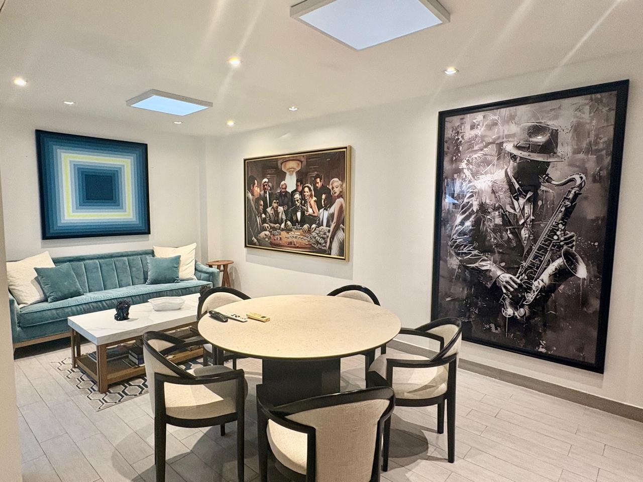 Sala residencial con tres cuadros de gran formato: saxofonista, escena de póker de íconos y abstracto geométrico
